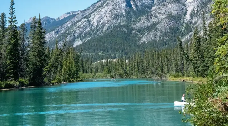 A canoe on the calm Bow River below Banff's mountains